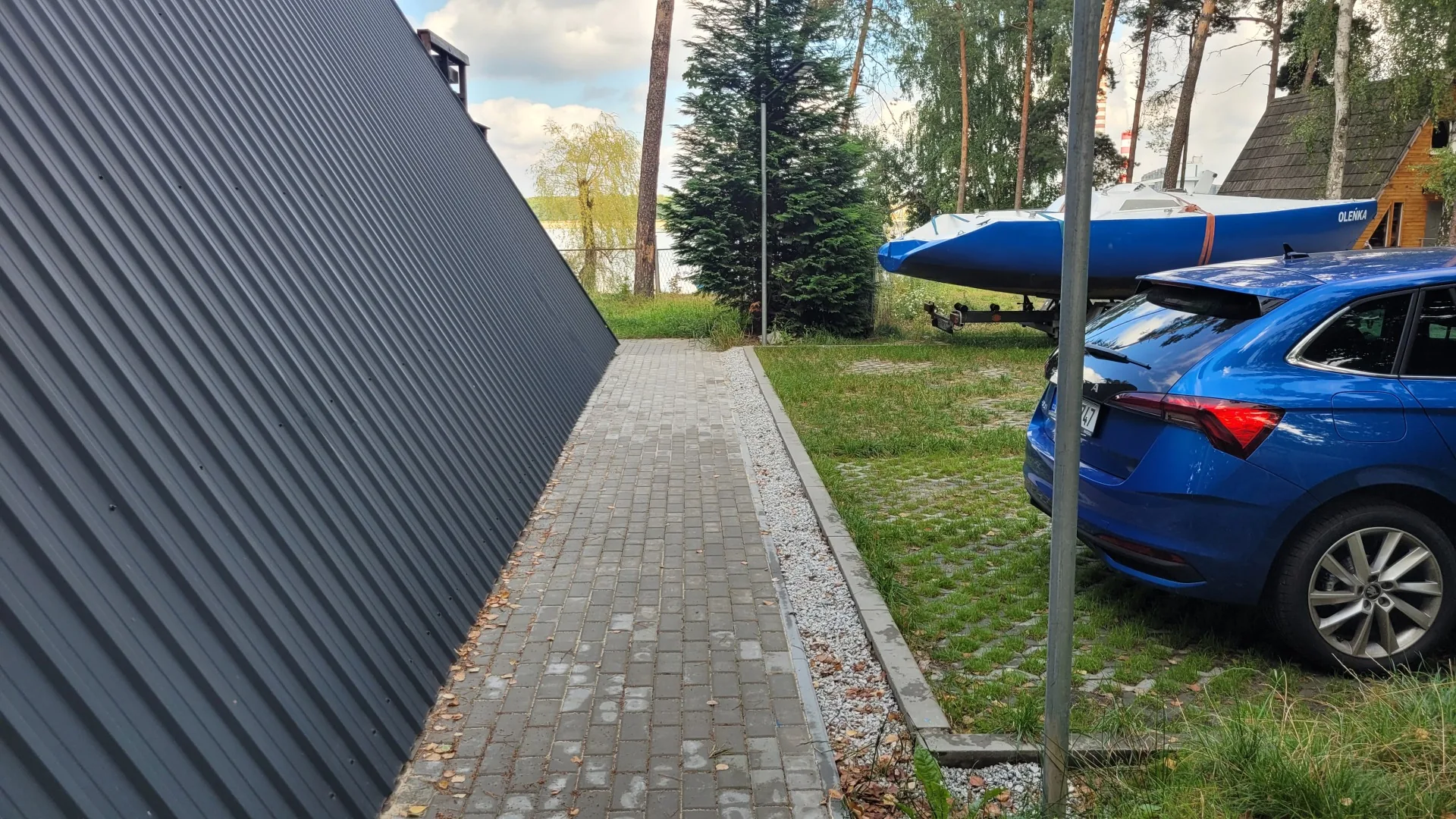 Wybrukowane dojście obok klubowego domku oraz jacht na przyczepie
